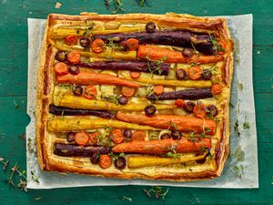 carrot tart on a sheet of parchment paper on a green wooden surface
