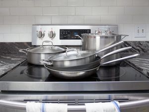 Cookware on a glass stovetop, including a stainless steel skillet, nonstick skillet, saute pan, rondeau, and stockpot.