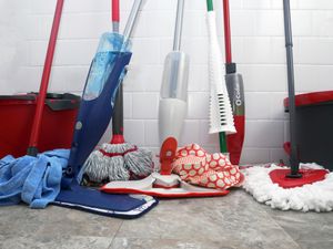 mops leaning against a white tile wall