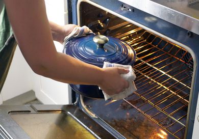 a person moving a dutch oven into the oven