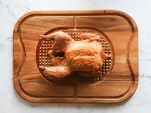 A roasted chicken on a wooden carving board